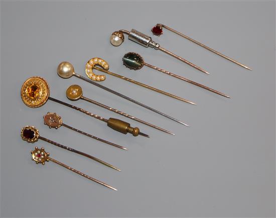 Ten assorted yellow metal and gem set stick pins.